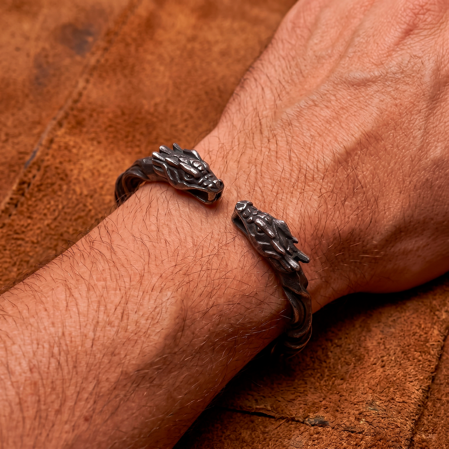 Silver dragon bracelet on a wrist against a brown leather background
