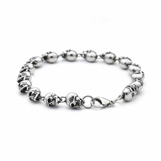 Silver bracelet with skull designs on a white background