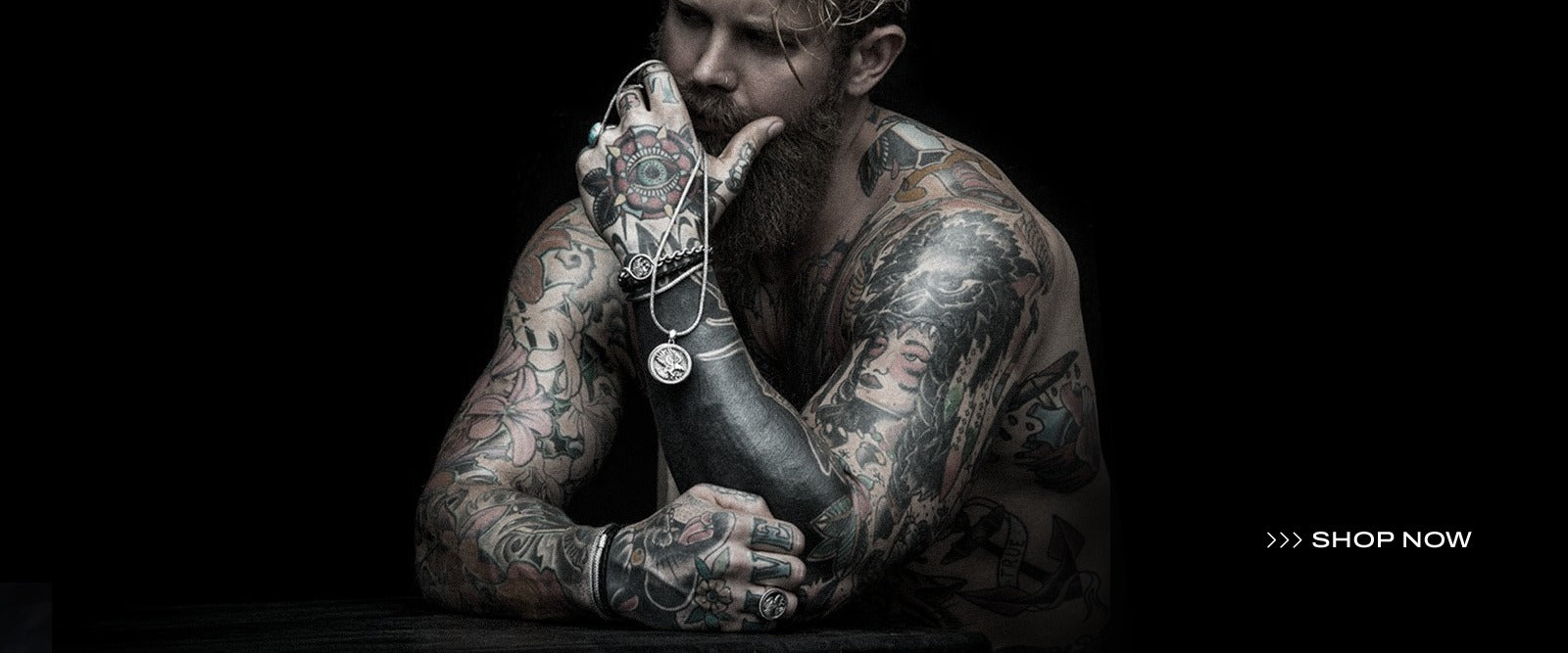 Man with tattoos holding a bottle with a dark background