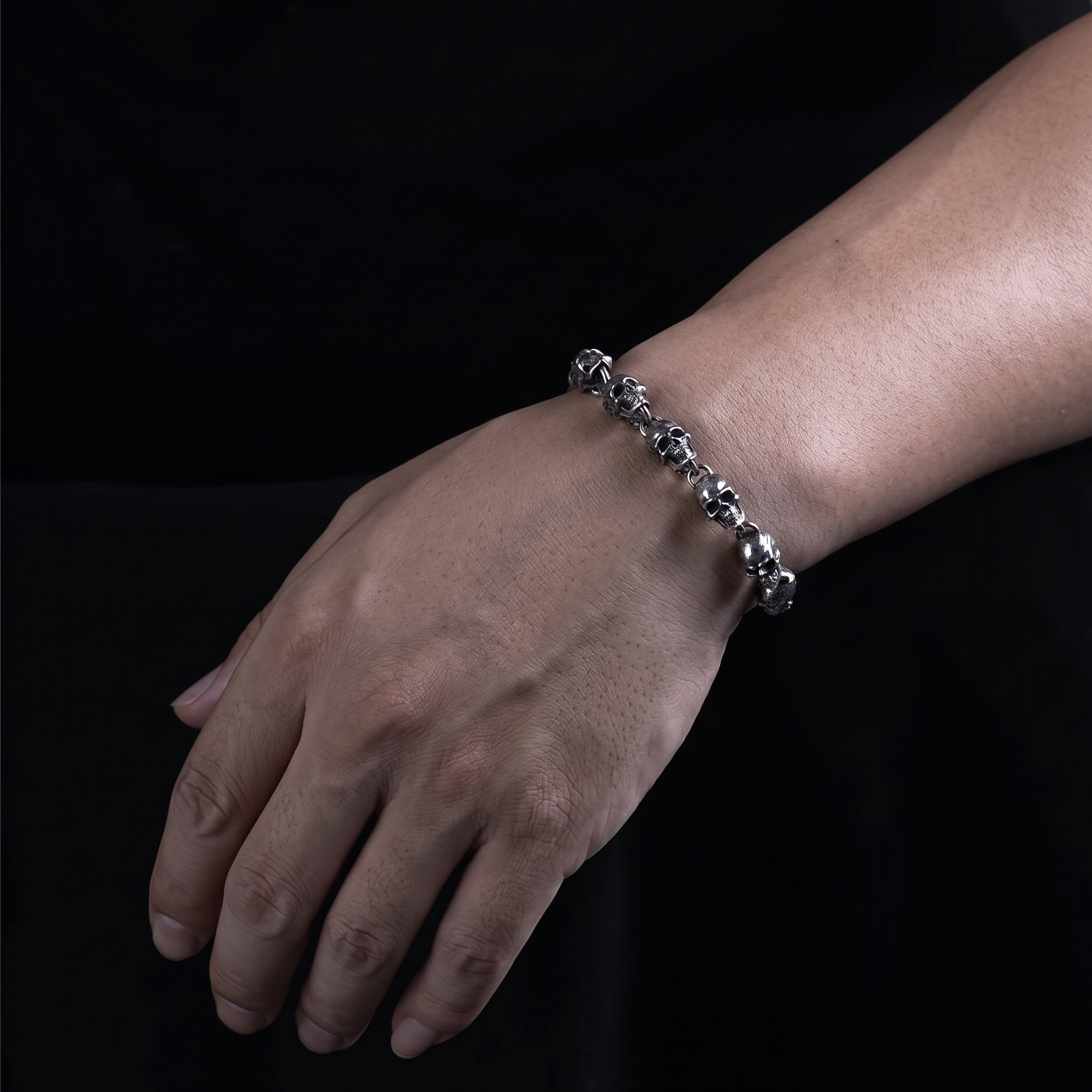 Hand wearing a silver bracelet on a black background